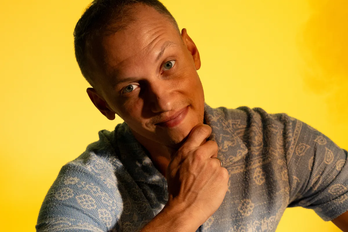 Artur Schmidt im Studio vor gelbem Hintergrund, nachdenklich, Hand am Kinn