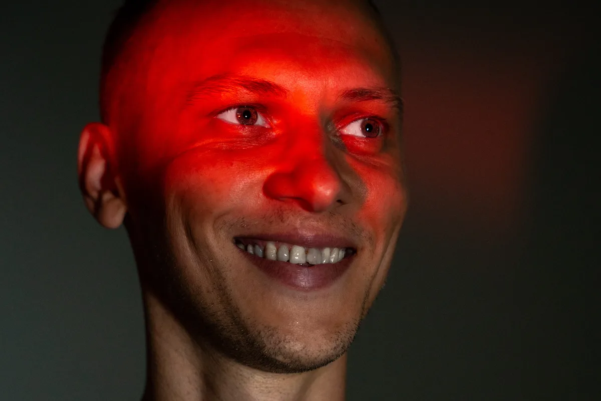 Artur Schmidt im Studio, rotes Licht auf dem Gesicht, lachend