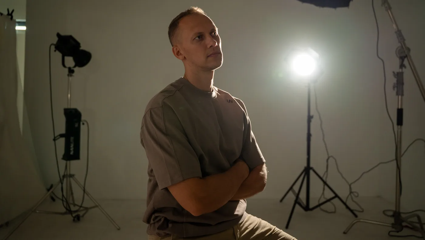 Artur Schmidt sitzt im Fotostudio, daneben Lampen und Stative